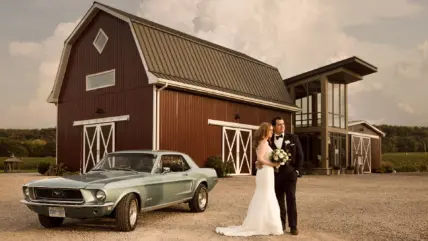 A newly married couple posing for pictures outside of the barn at Cave Spring Vineyard in Beamsville.