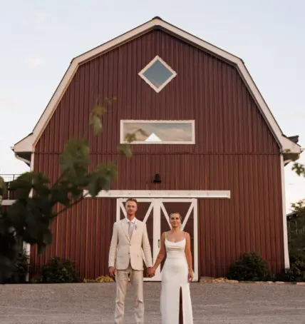 A newly married couple holding hands outside the barn at Cave Spring Vineyard in Beamsville.