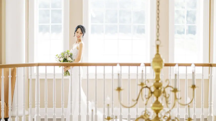 A bride standing on the staircase overlooking the foyer at Château des Charmes in Niagara-on-the-Lake.